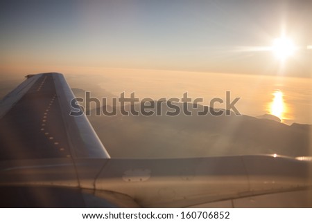 Airplane Wing view flying above clouds in sky sunset. view through airplane the window. Wing of an airplane in the sunset. vacation concept. plane wing and clouds. soft focus