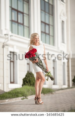 Beautiful happy woman with roses flowers outdoor. Sexy blond woman with rose bouquet in park. Valentines Day.