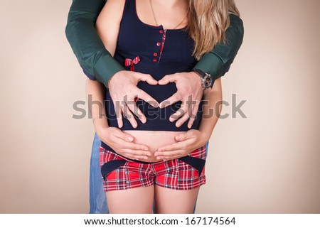 Husband hugs his pregnant wife, happy pregnancy. Young pregnant woman and man. Pregnant family. Studio shot