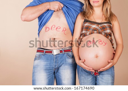Belly of pregnant wife and husband with funny inscription \