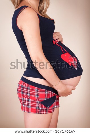 Happy young pregnant woman touching her belly. Healthy pregnancy. Beautiful pregnant girl in studio.