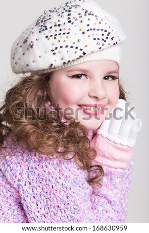 Lovely little girl in winter knitted hat pink scarf gloves and colorful cozy sweater. Kid fashion. Happy baby girl in woolen accessories at studio. Space and white background.