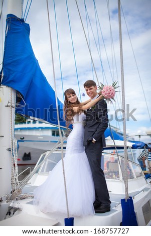Happy bride and groom on yacht at wedding day. Newlywed couple outdoors near sea.