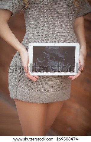 Pregnant woman with husband holding ultrasound scan on her tummy, healthy pregnancy. Happy pregnant couple outdoors. Pgegnant family. Concept.