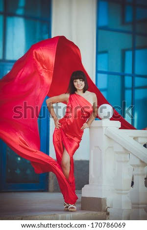 Vogue style woman in fashion red dress outdoors. Glamour beauty model in luxury red dress posing. Fashion photo of sexy woman, Vogue lady. Sensual woman in red dress. Tonned photo