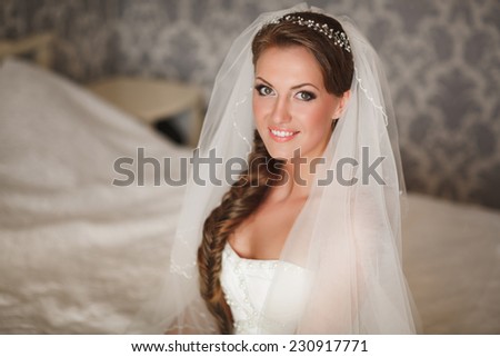 Beautiful young bride with wedding makeup and hairstyle in bedroom, newlywed woman final preparation for wedding. Happy Bride waiting groom. Marriage Wedding day moment. Bride portrait soft focus