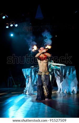Young sexual fakir man fire eater actor  eating fire dangerous fiery fascinating performance in circus at night  breathing fire blowing fire from his mouth and wonderful beauty arabic bellydancer