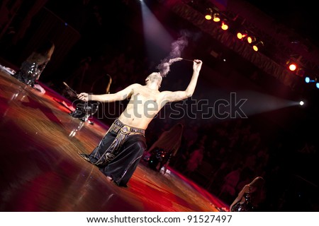 The young sexual fakir man fire eater actor  eating fire dangerous fiery fascinating performance in circus at night  and breathing fire blowing fire from his mouth
