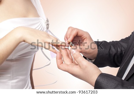  Groom putting golden ring on bride's finger during wedding ceremony