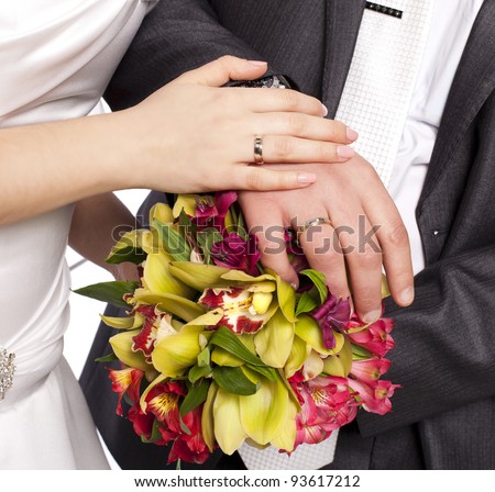 Hands with rings-Hands of bride and groom and rings with wedding bouquet loving couple closeup in studio isolated portrait on white background