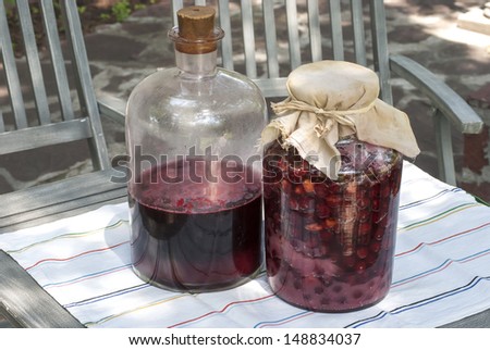 Large glass jars with sugar soaked sour cherries and alcohol fermentation for making homemade liqueur
