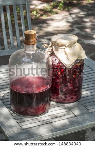 Large glass jars with sugar soaked sour cherries and alcohol fermentation for making homemade liqueur