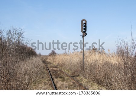 Abandoned rail line and empty railway traffic light in dry grass field