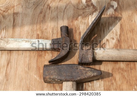 Old weathered grunge hammers and adze head closeup on plywood surface