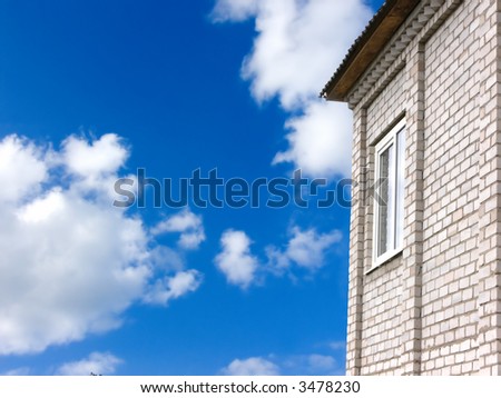 Window in a wall of the brick house on a background of the blue summer sky