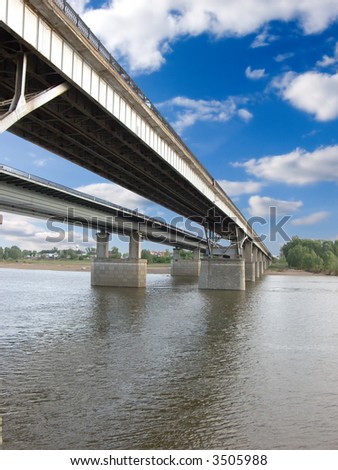 The large bridge through the river. The photo is created in the Russian province in the summer.