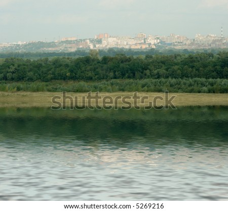 Landscape with the image of large city behind the river. Russia. Ural. Realistic photomontage.