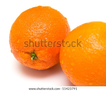 The ripe whole oranges covered by drops of a water. Isolation on white, shallow DOF.