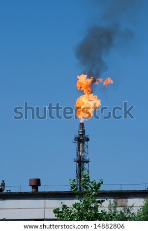 Photo about problems of ecology. An industrial part of the Russian city. A huge torch from burning by-products of manufacture of fuel.