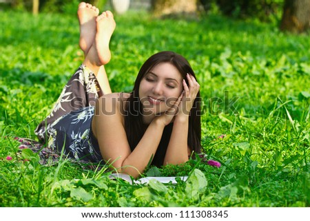 portrait of a young beautiful woman, dreaming, lying on the grass
