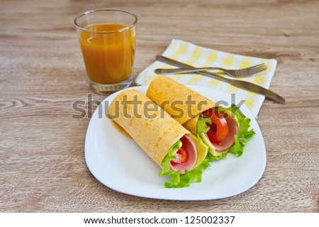 Wrapped tortilla sandwich rolls with lettuce, cheese, tomatoes and ham