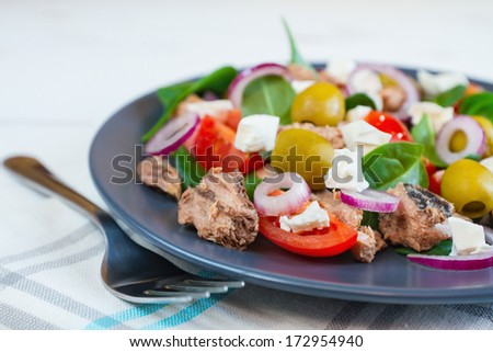 Salad of tomatoes, cheese, olives, red onion, tuna and spinach leaves