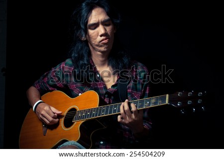 Long hair guy playing guitar acoustic