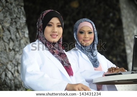 Two Women Doctor With Scarf using laptop with friend
