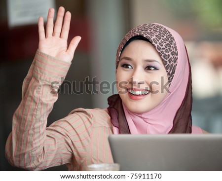 young muslim woman in head scarf say hi to friend in cafe
