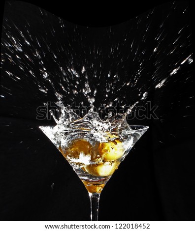 Color photo black background olives splashing in a martini glass