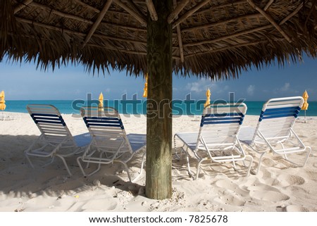 sun beds with thatched sun shade on beach with turquoise sea