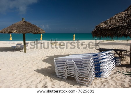 sun beds with thatched sun shade on beach with turquoise sea