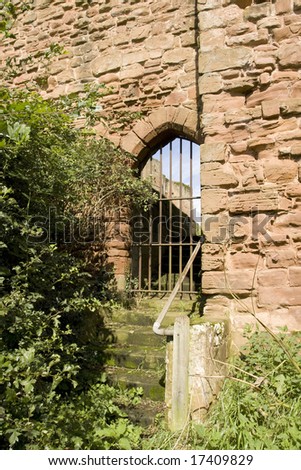 stairs leading up to closed metal gate in castle wall