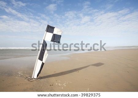swimming warning flags blowing in the wind on a beach