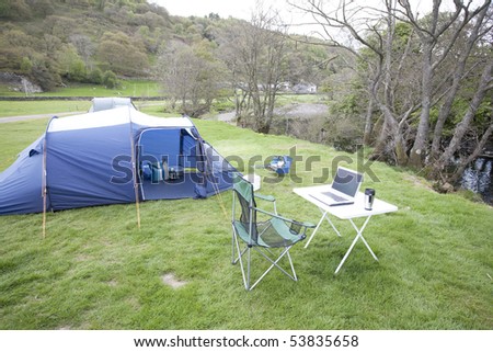 laptop computer on a table next to a tent for outdoor computing