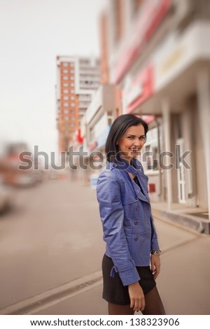 Attractive woman is standing on the street in a blue jacket