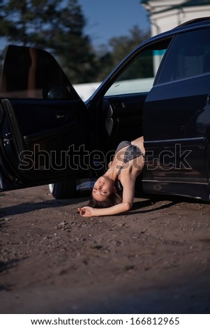 Dead woman in bikini hanging out of motor car doorway.