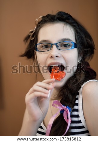 portrait of girl eating red candy.