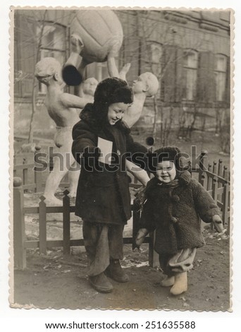 The old Soviet Black and white photo family house. Two boys in the winter on a background of the statue.