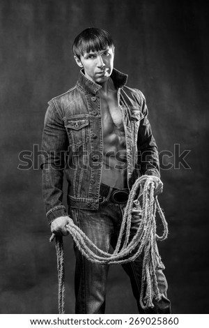 Young athletic man in jeans jacket with a rope.