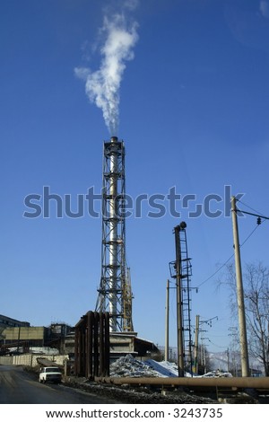Smoking pipe of a factory on a background of the blue sky