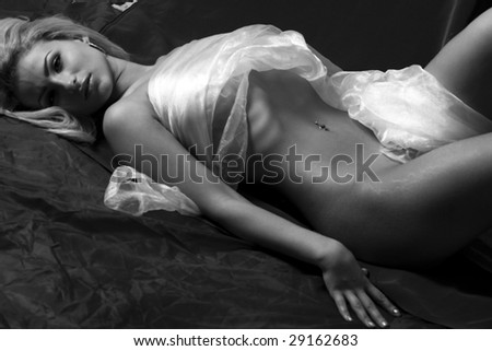 The charming bared girl lies having wrapped in a white fabric