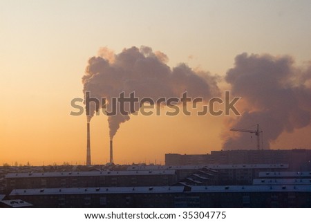 Smoking pipes of factory against a sunset