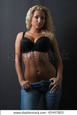 Half body portrait of sexy young blond woman wearing lingerie, dark studio background.