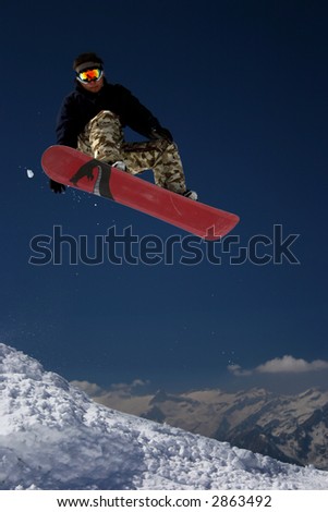 Snowboarder in moro desert pants jumping high - winter mountain action scene