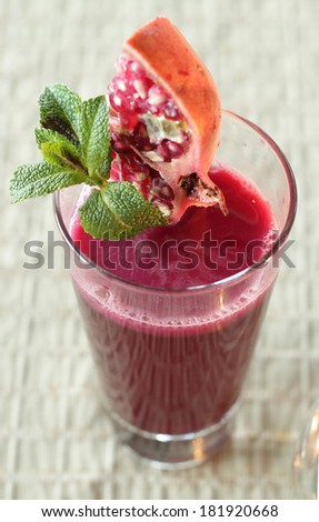 Pomegranate juice. Freshly squeezed pomegranate juice in glass with piece of pomegranate, decorated with mint leaf