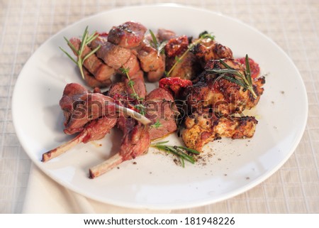 grilled meat. meat on the grill cuts of lamb, beef and chicken on white plate, grilled with potatoes, bacon, pepper, rosemary and thyme, food for picnic and large company