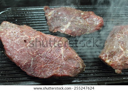 Steaks on the grill. Sirloin tip. Raw steak meat black angus roast on the grill and smoke. Food, lunch, dinner