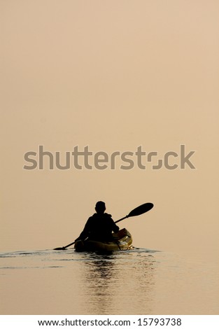This person was about a hundred yards off shore on the sound paddling a kayak towards setting sun.  The sky and the water almost blended into one background except for the sun itself.