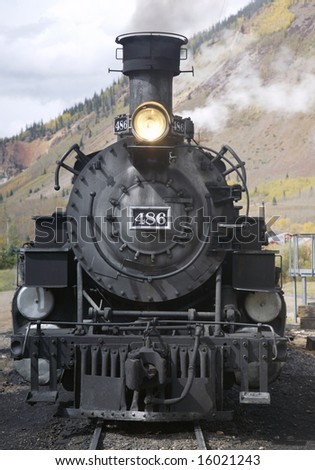 This is a photo of the front of an old steam locomotive getting ready to pull a group of passenger cars through the mountains of Colorado.